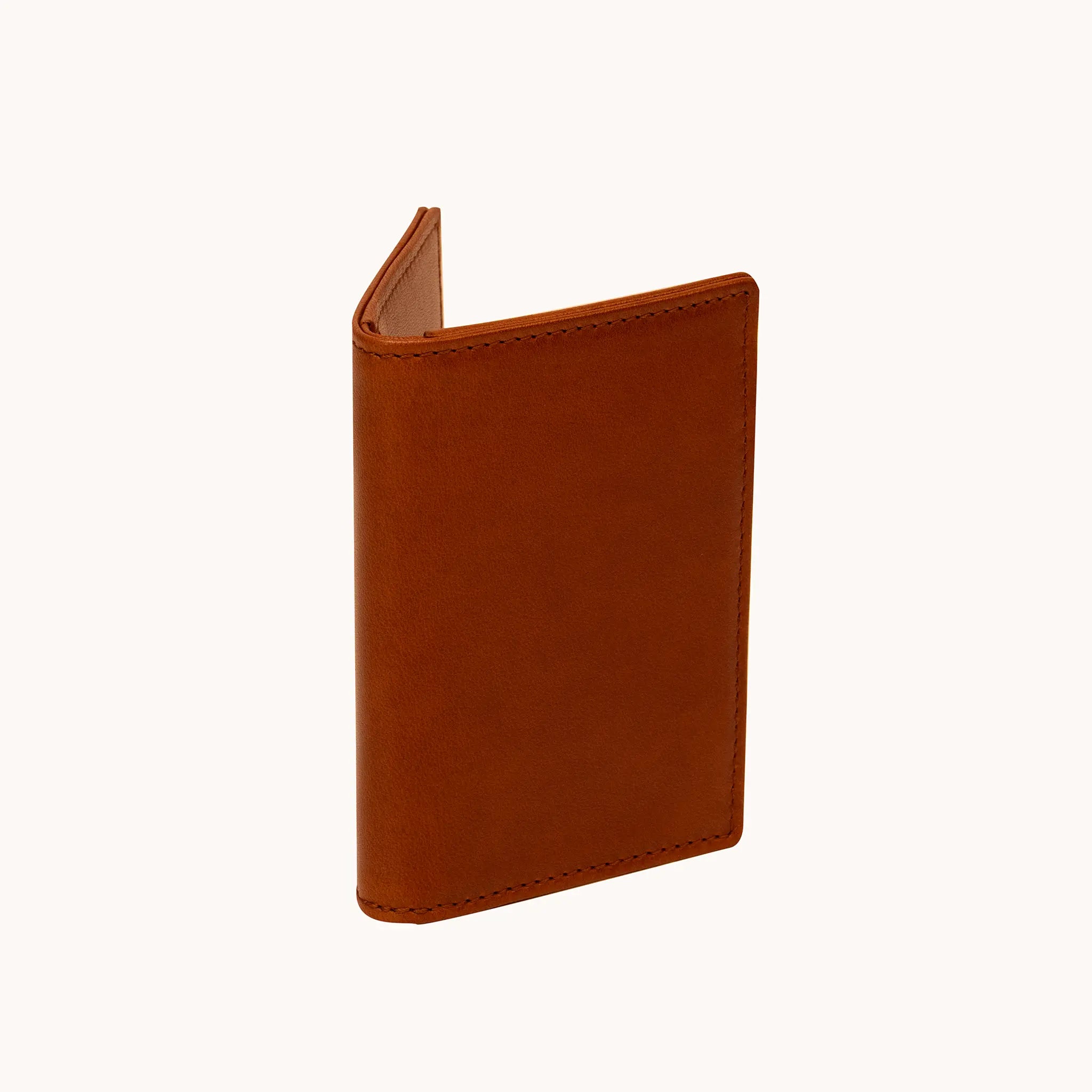 Lunburg Small Vertical Signet Wallet in Heritage Amber at a three-quarter angle, slightly open, showing the slim profile, folded edge construction, and edge stitching in vegetable-tanned Perpetual Leather.