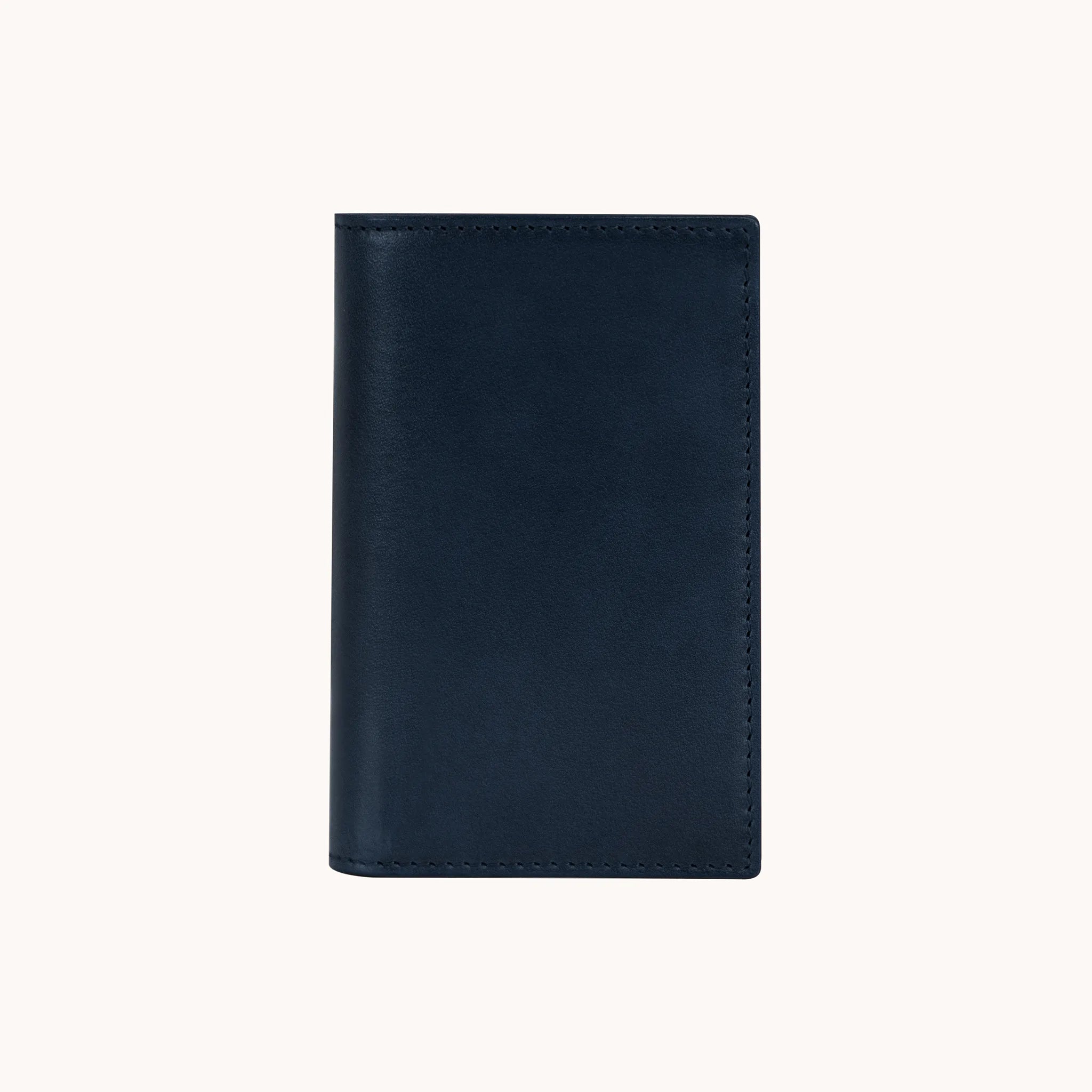 Lunburg Signet Vertical Bifold in Nocturnal Sapphire, front view closed, showing the clean face of vegetable-tanned Perpetual Leather (from Tempesti) with folded edge construction and no visible raw edges.