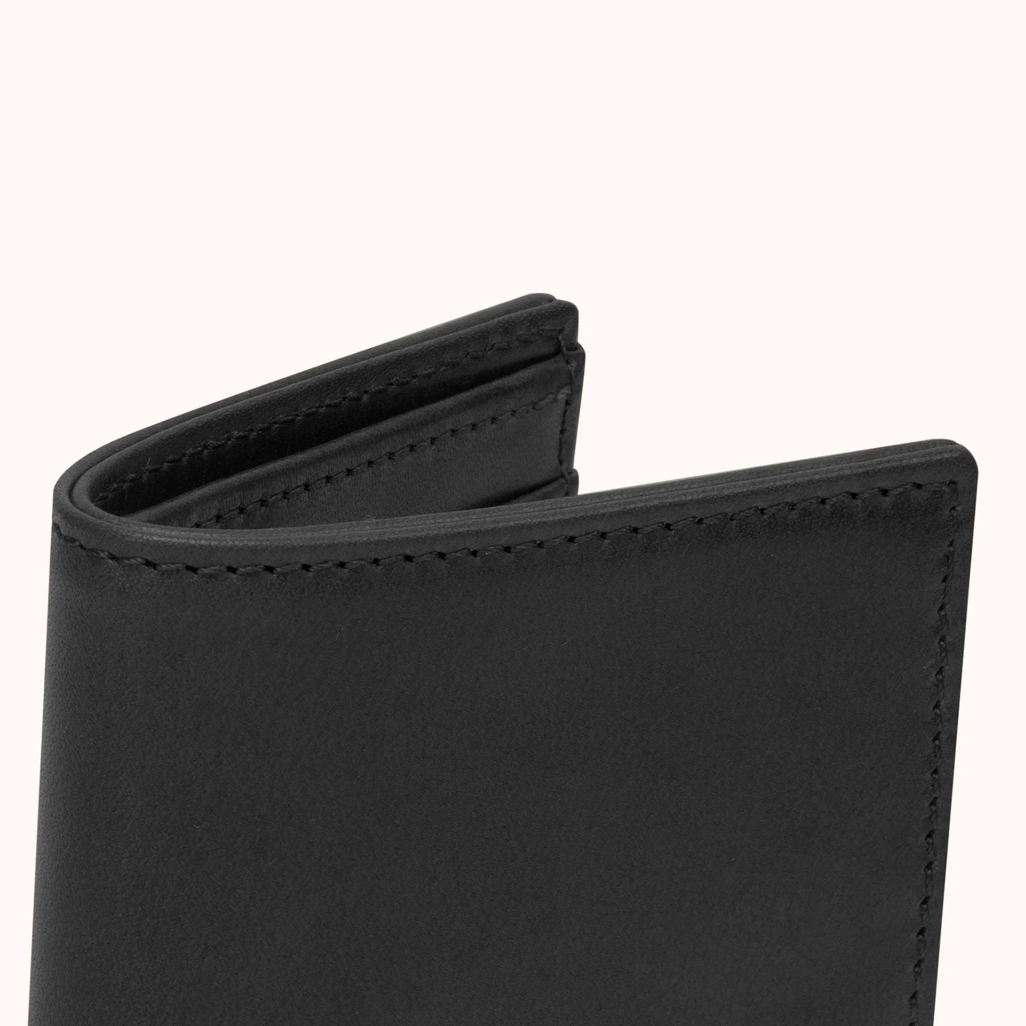 Lunburg Signet Vertical Bifold in Burnt Timber, close-up detail of the spine and upper card slot edges showing the folded edge construction of Rempliage where no raw edges are visible, in vegetable-tanned Perpetual Leather (from Tempesti).