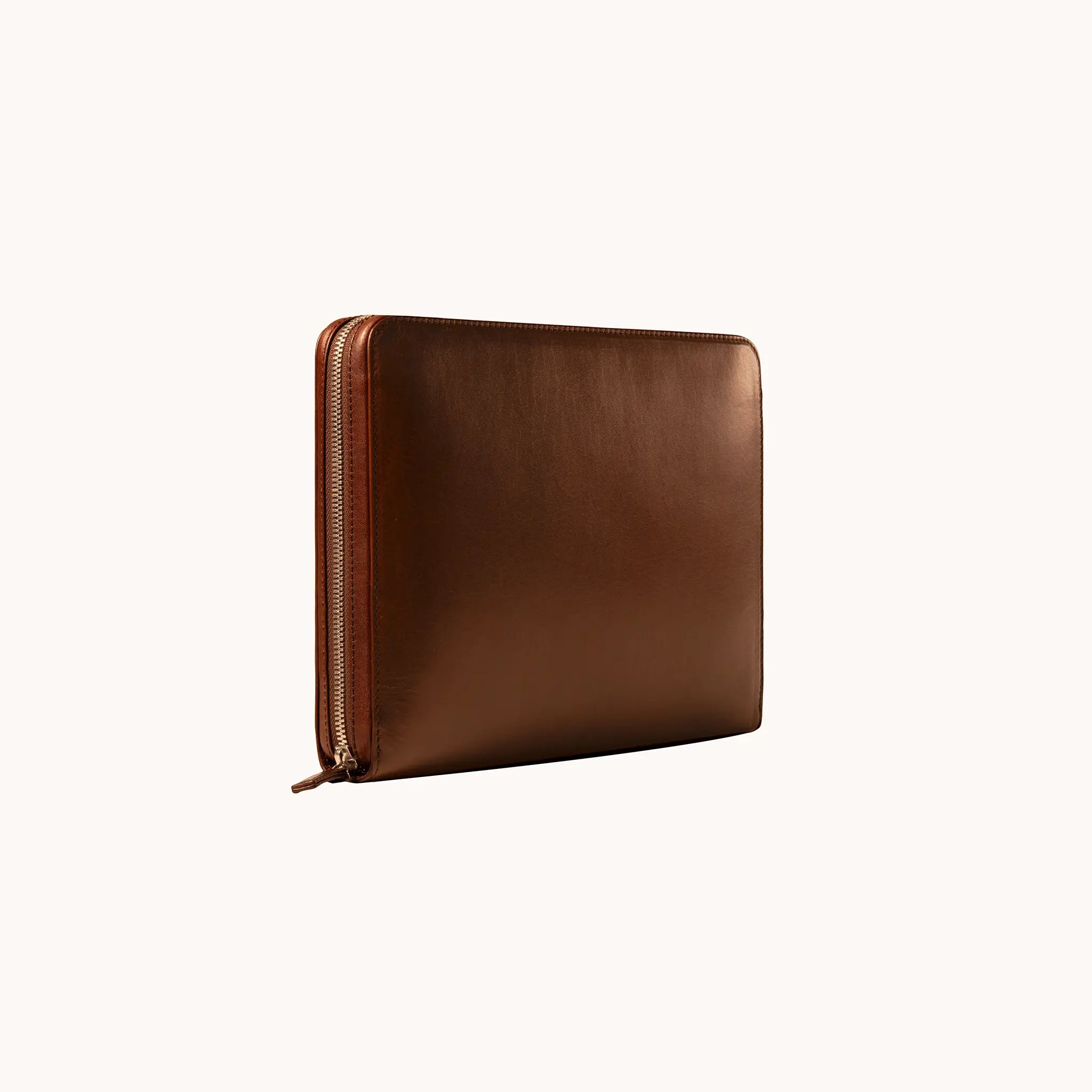 Lunburg Memoir Workstation in Deep Mahogany, three-quarter view showing the exterior grain, YKK Excella zipper running along the spine, and leather zipper pull, in vegetable-tanned Perpetual Leather (from Tempesti) with folded edge construction.